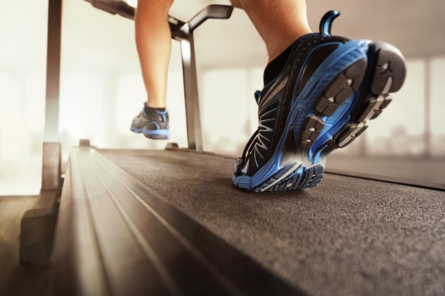 Man running in a gym on a treadmill concept for exercising, fitness and healthy lifestyle