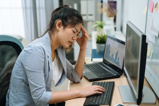 Stressed frustrated young asian businesswoman reading bad email internet news on computer feeling sad tired