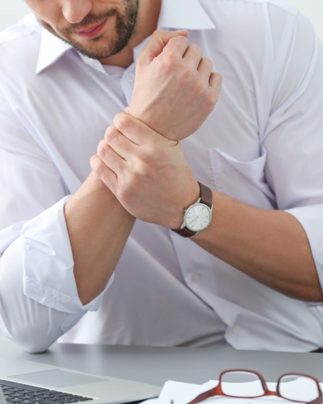 man suffering from wrist pain in office