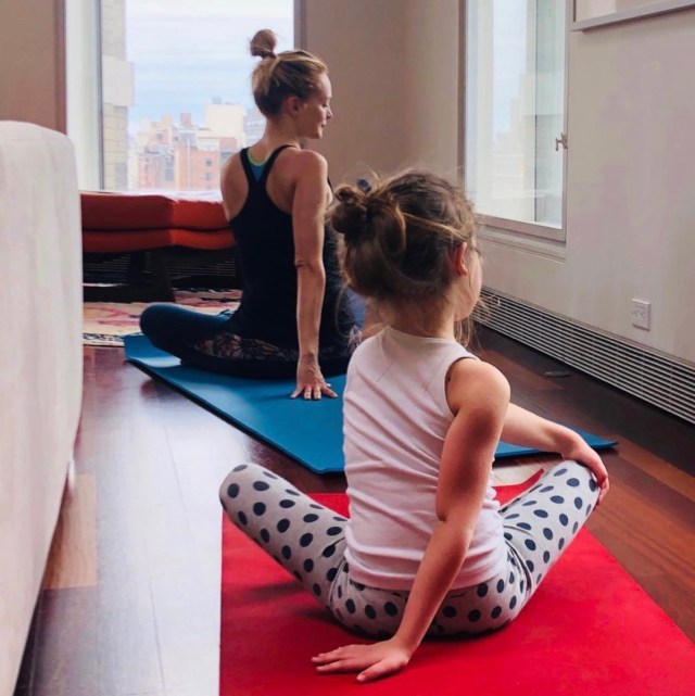 heather graham with her back to the camera doing yoga with a child