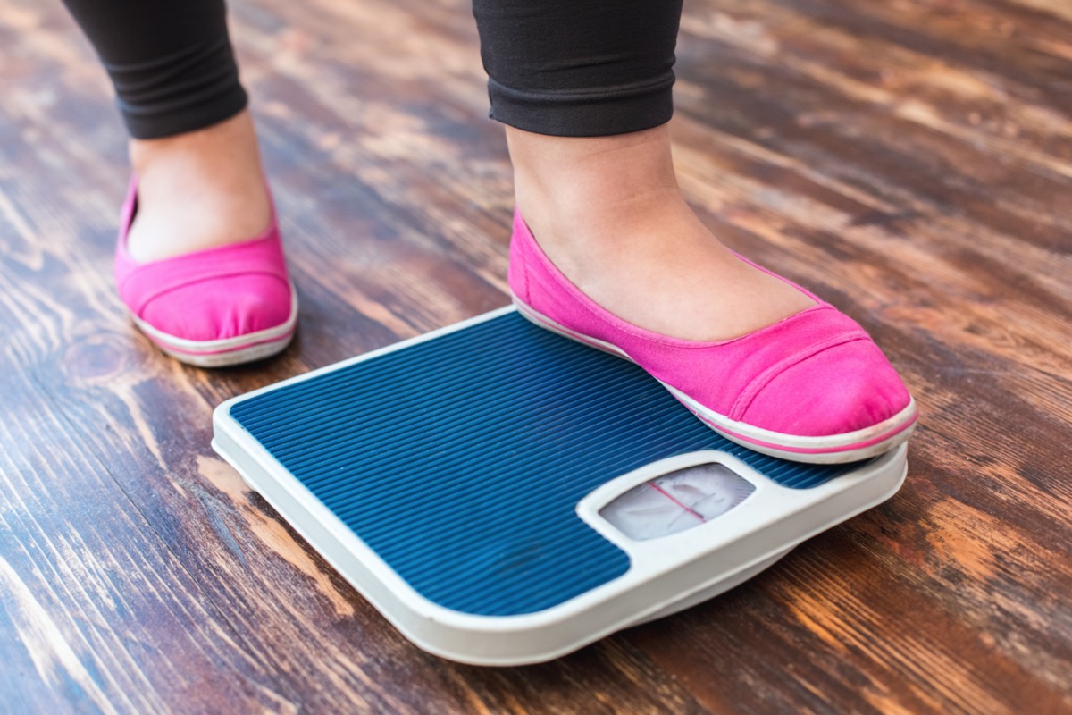 woman stepping on scale in pink flats