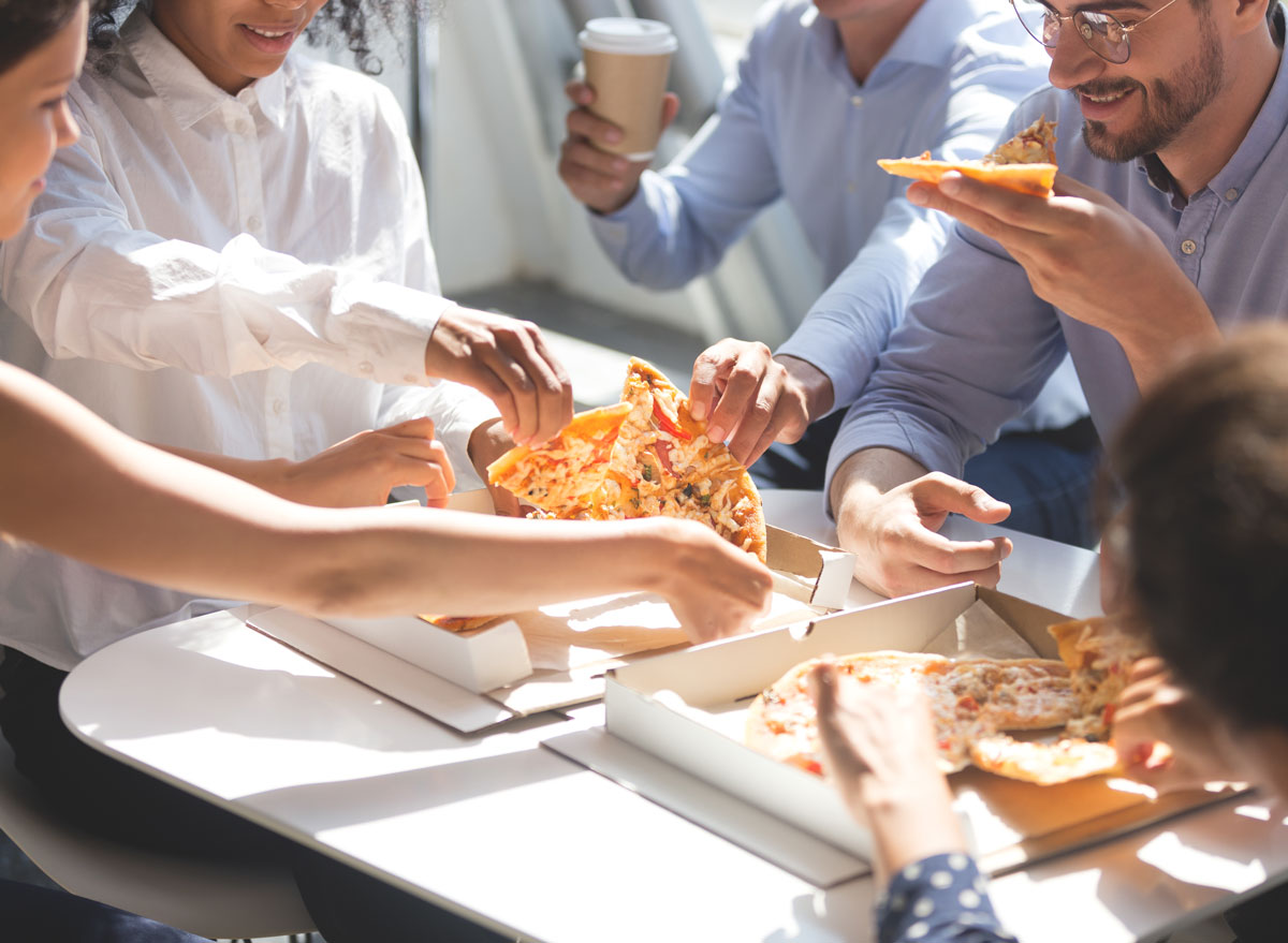 Coworkers quickly grabbing slices of pizza at work