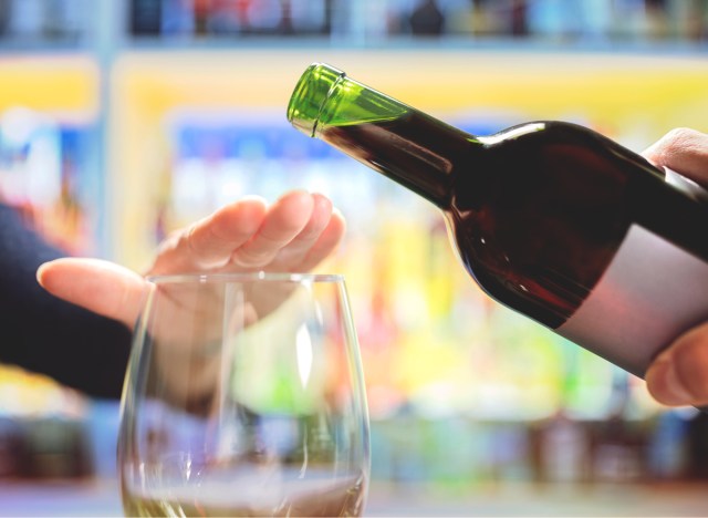 woman refusing or saying no to being poured a glass of wine alcohol