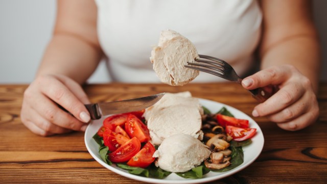 Woman eating baked chicken breasts with salad.