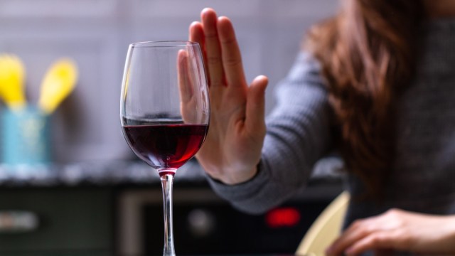 woman turning down glass of red wine