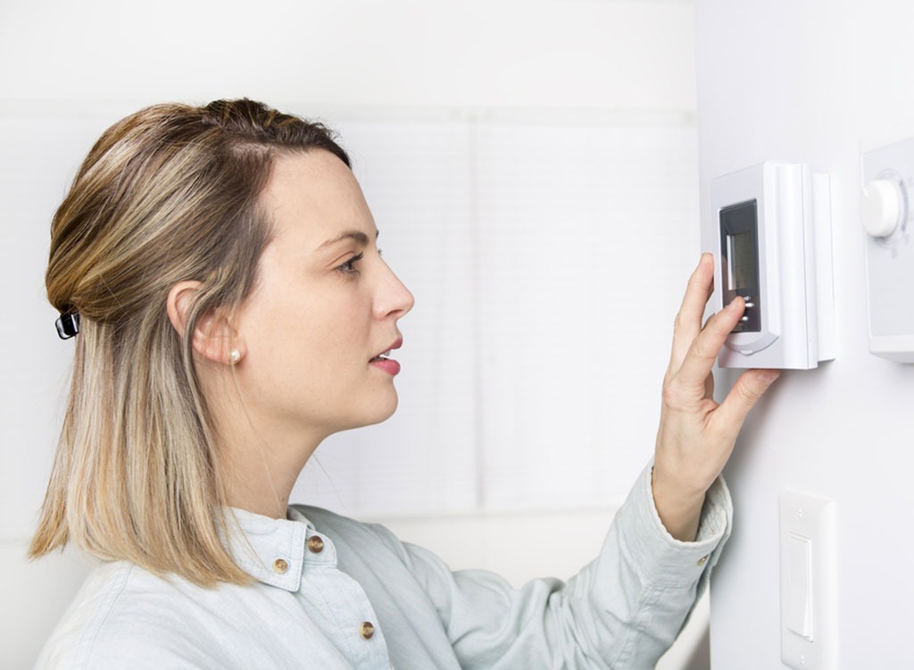 Woman setting thermostat