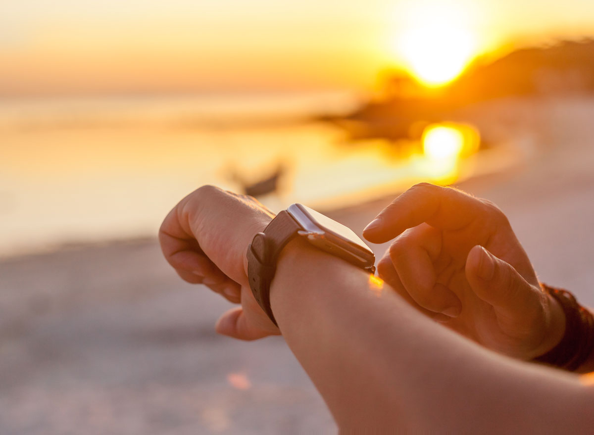 Looking at watch during run exercise on beach