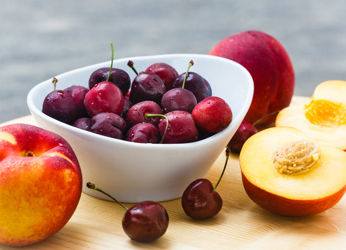 High fodmap fruits cherries peaches on wooden cutting board