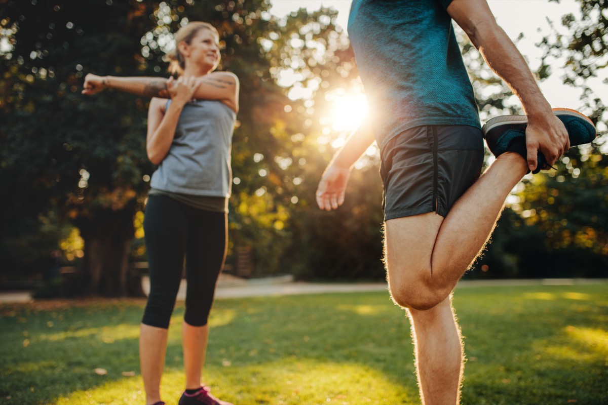 A man and a woman stretching in the park.