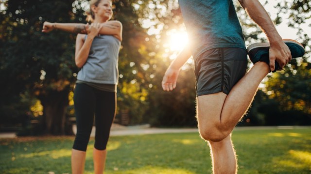 A man and a woman stretching in the park.