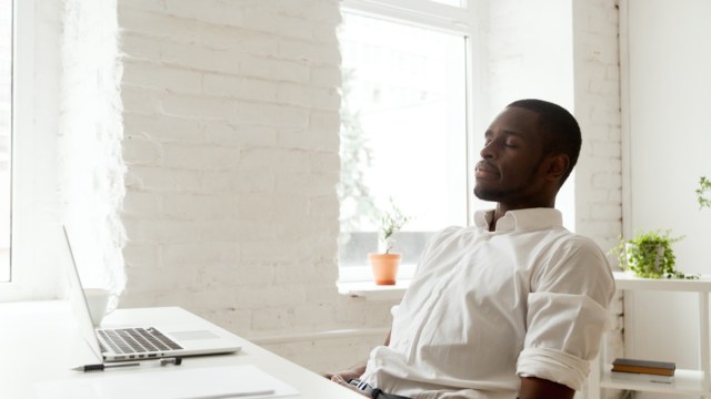 man relaxing after work breathing fresh air sitting at home office desk with laptop