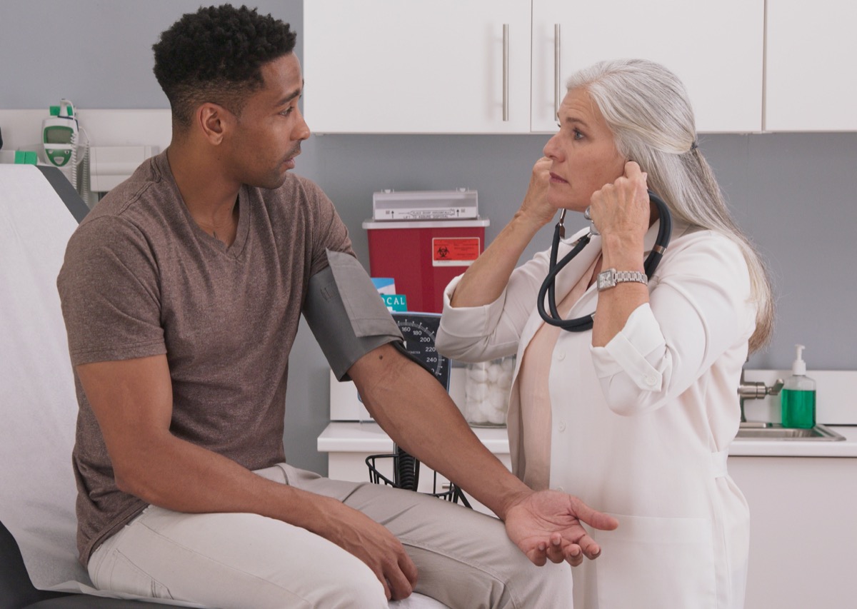 female physician checking male patients blood pressure at clinic