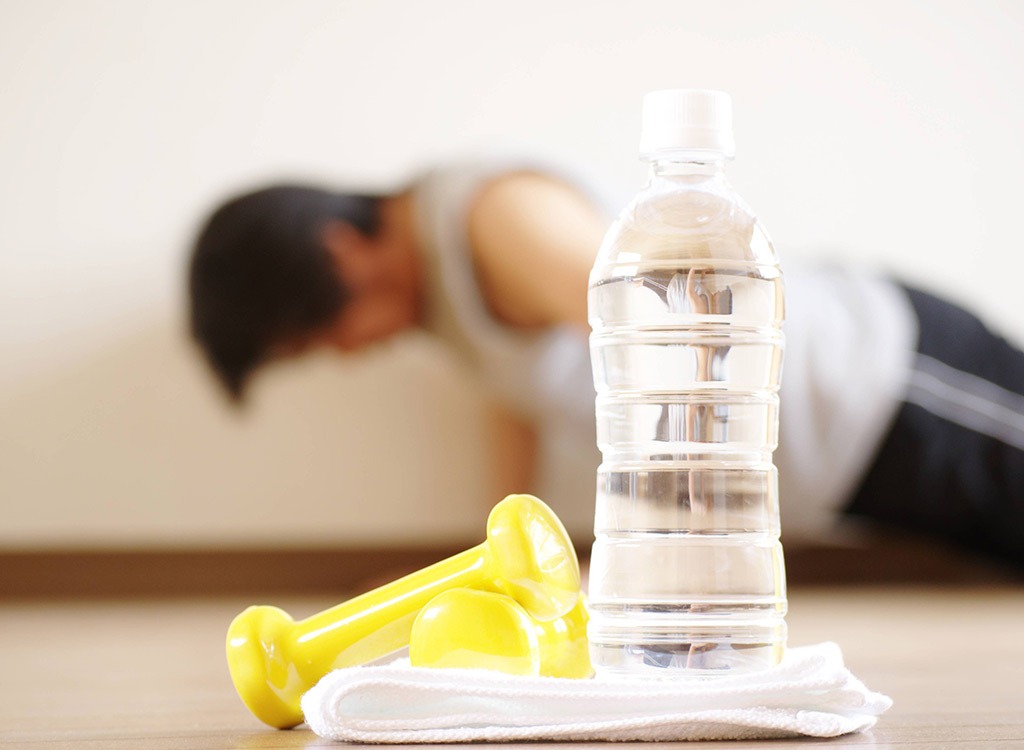 Plastic water bottle with man doing pushups in background