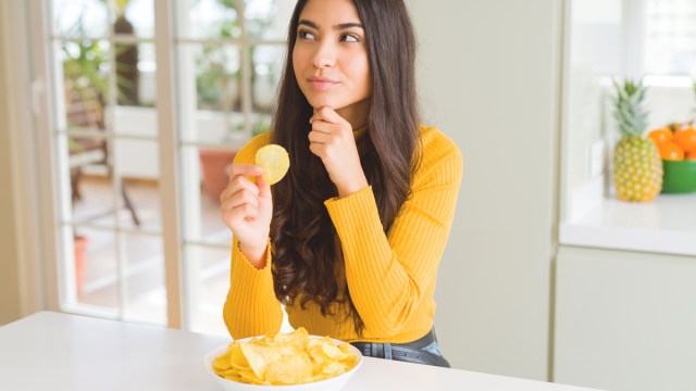 woman thinking about eating a potato chip and practicing mindful eating