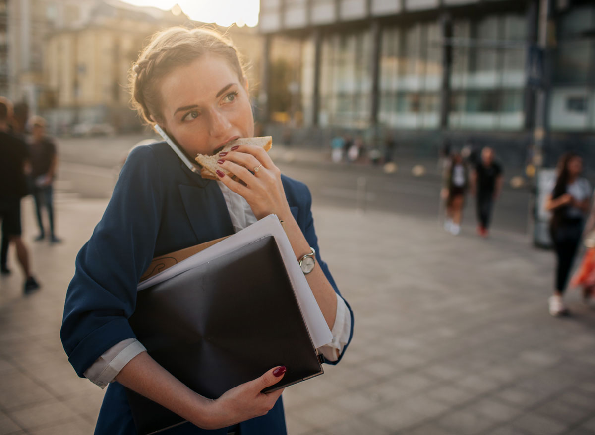 Woman eating while talking walking on the go