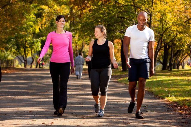 two women and a man walking together in a park