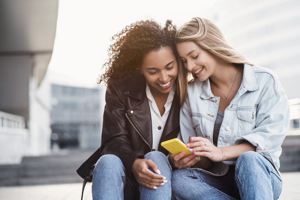 women looking on phone together apps to find friends