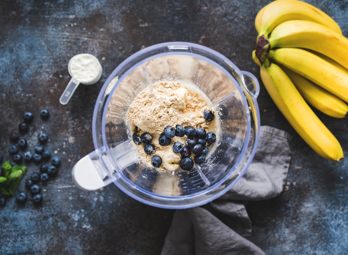 making a smoothie with protein powder blueberries banana in blender