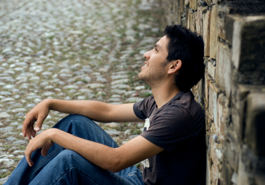 man smiling sitting on the sidewalk signs your twin flame is communicating with you  